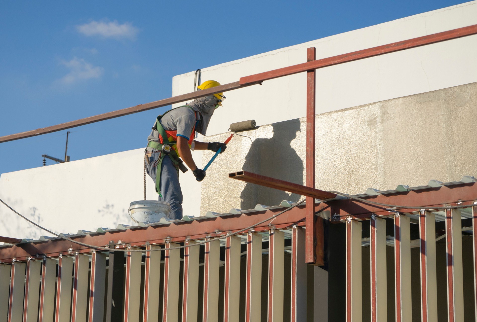builder worker painting facade of high-rise building with roller